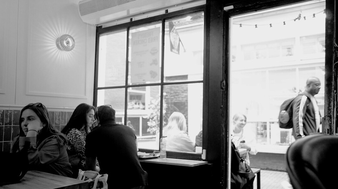 Group of friends talking and laughing around a cafe table