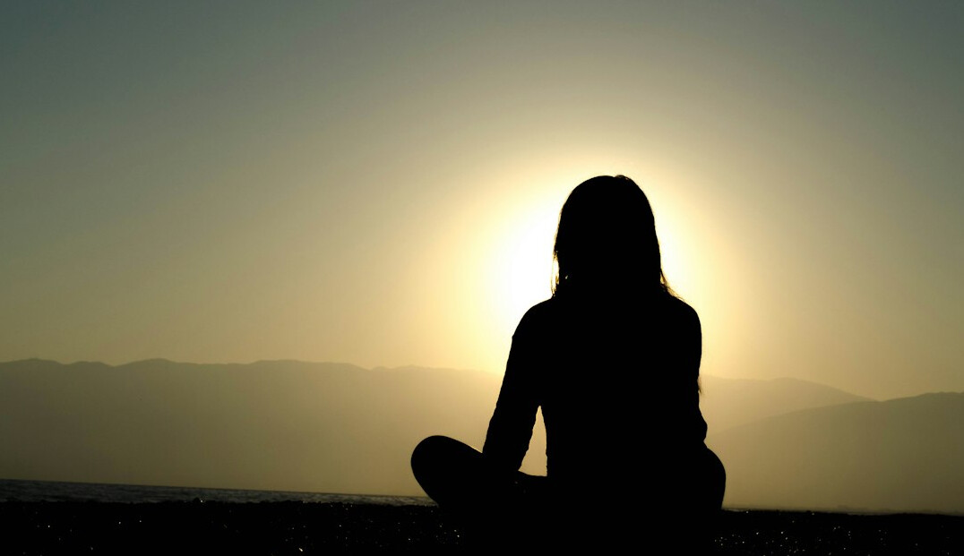 Woman sitting calmly with eyes closed in a bright room